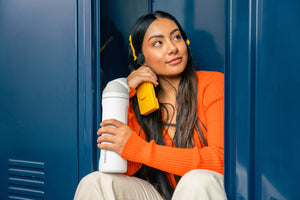 Owala water bottle held by a student outside locker at school listening to music