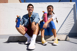 Guy and girl with Owala water bottles sitting and smiling