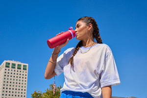 Girl outside a big building drinking from an Owala water bottle